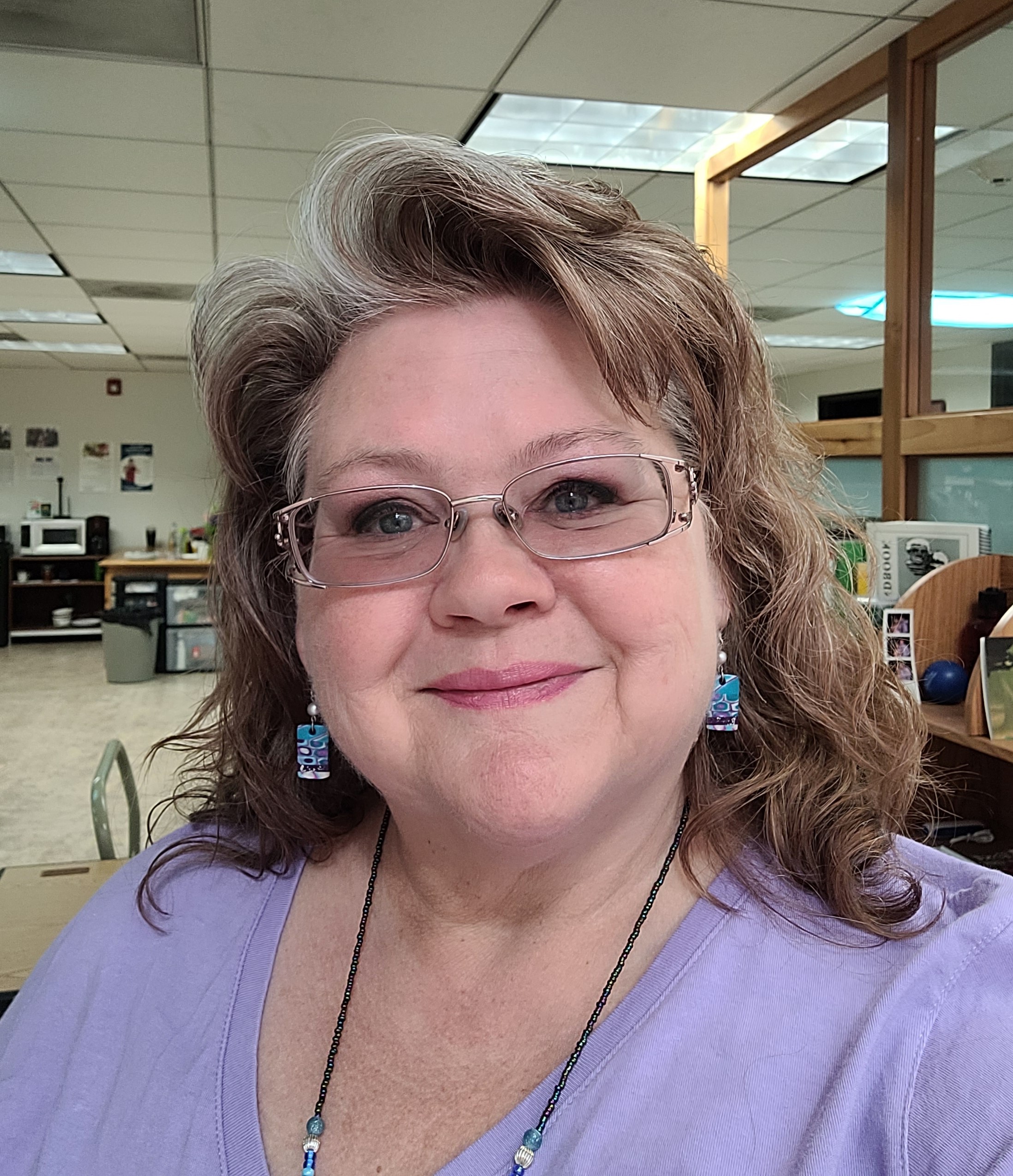 Tracy photo_cropped Photo of Program Manager Tracy Agiovlasitis wearing glasses, a purple top, and colorful blue earrings